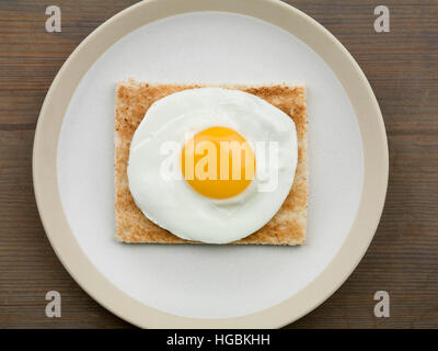 Ein frisch zubereitetes Frühstück von einem Spiegelei auf Toast oder leichtes Mittagessen Sunny Side Up serviert auf einem Teller mit keine Menschen als Flach Zusammensetzung Stockfoto