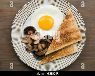 Gesundes Frühstück von einem einzigen Fried Egg Sunny Side Up Pilze und Toast serviert auf einem Teller mit einem Flach Zusammensetzung und keine Leute Stockfoto