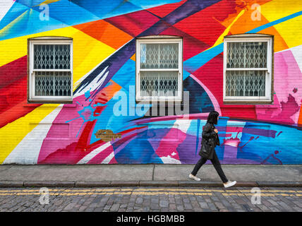 Einsame Mädchen geht vorbei an regenbogenfarbige Streetart Stockfoto