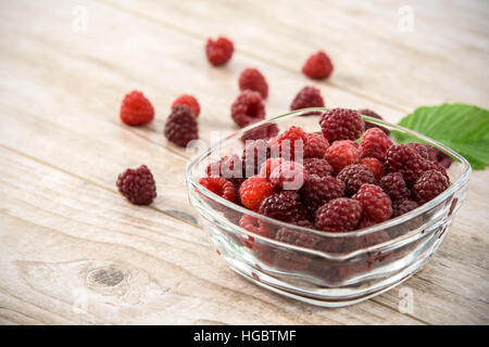 Saftigen und reifen Himbeeren in eine Glasschüssel auf einem Holztisch vintage Stockfoto