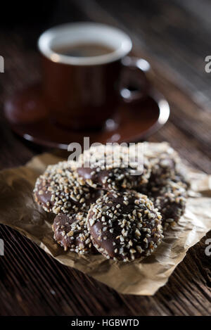 Cookies mit Schokolade und Nüssen bedeckt. Mit Kaffee auf dunklem Hintergrund. Stockfoto