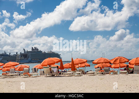 Orange Sonnenschirme mit Kreuzfahrtschiffen im Hintergrund in St. Maarten Stockfoto