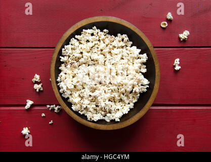 Offene Schüssel tauchte Popcorn auf rotem Grund aus Holz Stockfoto