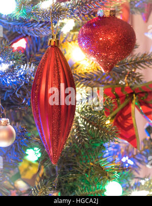 Christbaumschmuck.  Leuchtend rote Urlaub Christbaumschmuck von Niederlassungen auf einen kleinen faux indoor Baum hängen. Stockfoto