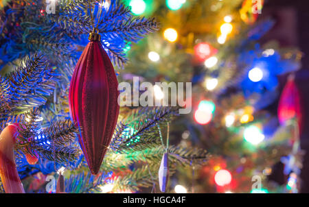 Christbaumschmuck.  Leuchtend rote Urlaub Christbaumschmuck von Niederlassungen auf einen kleinen faux indoor Baum hängen. Stockfoto