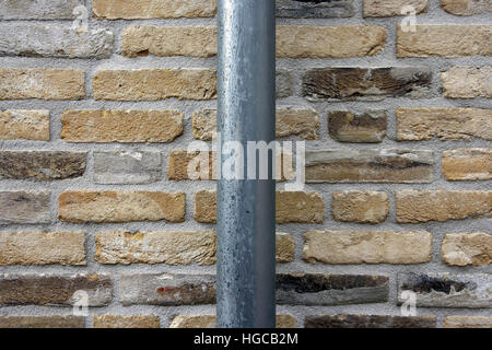 Eine neue Mauer mit einem Fallrohr. Stockfoto