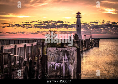 Küste Leuchtturm Sonnenaufgang. Sunrise-Horizont mit einem Leuchtturm und historischen dock im Vordergrund in St. Ignace, Michigan. Stockfoto