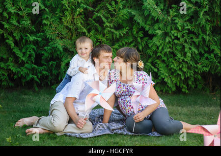 junge Familie sitzt auf Rasen im Sommerpark Stockfoto