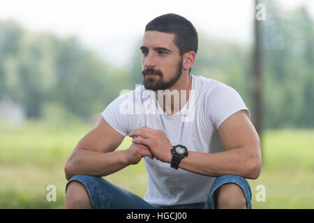 Porträt eines jungen Mannes sitzen auf Rasen - hübscher Kerl Ruhe in der Natur - im freien - außerhalb Stockfoto