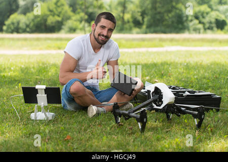 Nahaufnahme der junge Ingenieur Mann überprüfen die Kamera von einer Drohne mit Hand im Park Stockfoto