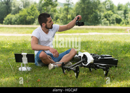 Nahaufnahme der junge Ingenieur Mann überprüfen die Kamera von einer Drohne mit Hand im Park Stockfoto