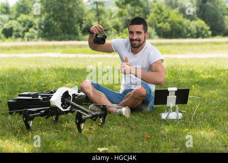 Nahaufnahme der junge Ingenieur Mann überprüfen die Kamera von einer Drohne mit Hand im Park Stockfoto