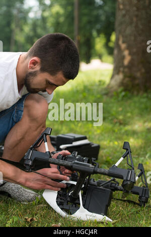 Nahaufnahme der junge Ingenieur Mann überprüfen die Kamera von einer Drohne mit Hand im Park Stockfoto