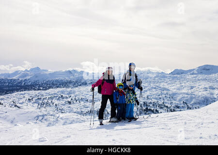 Junge glückliche Familie mit zwei Kindern, jungen Brüder, Skifahren im österreichischen Skigebiet an einem sonnigen Wintertag Stockfoto