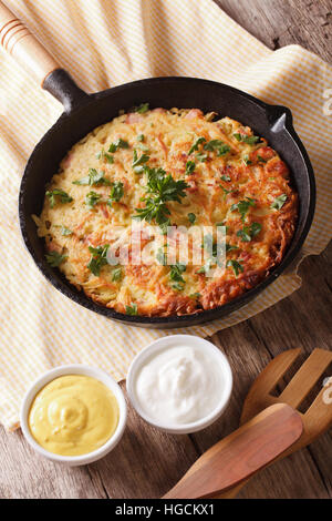 Rustikale Kartoffelpuffer mit Kräutern Nahaufnahme in einer Pfanne auf dem Tisch. vertikale Stockfoto