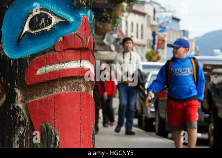 Totem und Touristen zu Fuß in den Straßen von Juneau. Alaska, USA. Die Stadt und Bezirk von Juneau ist die Hauptstadt von Alaska. Es ist eine einheitliche Spielplätzen Stockfoto