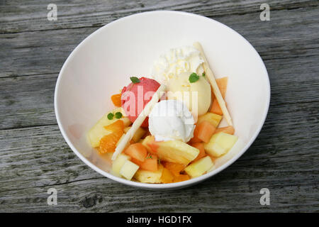 Verschiedenen Geschmacksrichtungen von Speiseeis in einer Schüssel mit etwas Obst und Schokolade-Sticks. Stockfoto