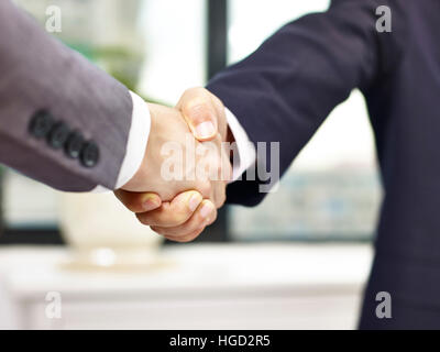 Nahaufnahme, niedrigen Winkel Aussicht auf einen festen Händedruck im Büro von zwei asiatischen Geschäftsleuten. Stockfoto