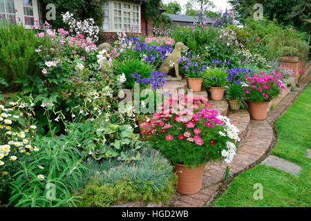 Bunte Garten-Terrasse mit gemischten Beeten und bepflanzten Container machen eine sehr attraktive vor einem Landhaus anzeigen Stockfoto