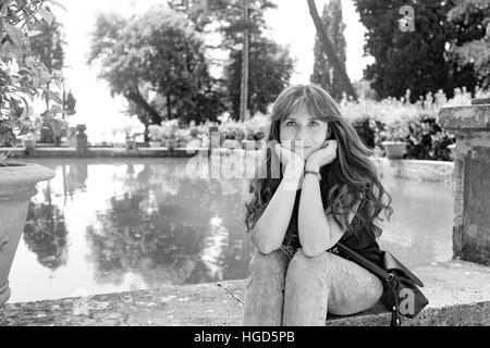 Nettes Mädchen mit langen Haaren, die in der Nähe von einem künstlichen See und ein Zitronenbaum posiert Stockfoto