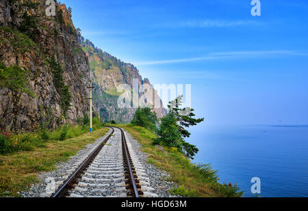 Eingleisige Bahnstrecke am Rand des Landes zwischen steilen Felsen und den Baikalsee. Irkutsker Gebiet. Russland Stockfoto