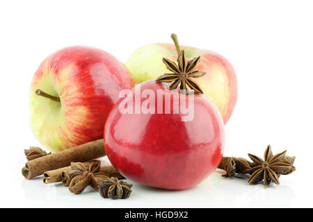 Drei glänzende frische rote Elstar Äpfel (Malus Domestica) mit Zimt und Sternanis, auf einem weißen Hintergrund. Stockfoto