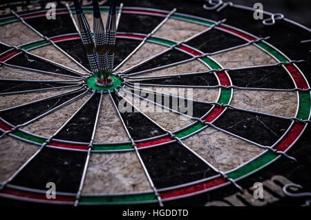 Drei dart-Pfeile schlagen in der Ziel-Mitte der Dartscheibe Stockfoto