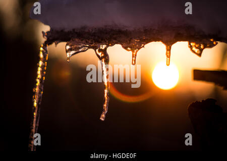 Unterstützt von einem farbenfrohen Sonnenuntergang Winterhimmel Eiszapfen Stockfoto