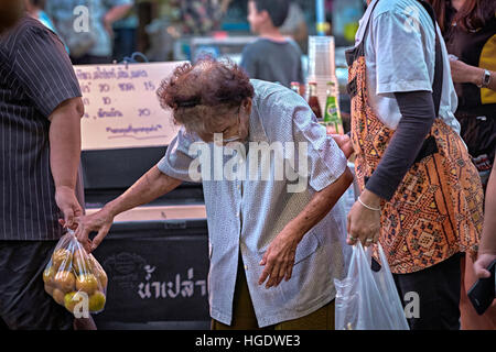Leute helfen einer sehr alten Dame beim Einkaufen. Thailand S. E. Asien Stockfoto