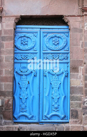 Leuchtend blau geschnitzte hölzerne Tür-Set in Steinwand in Cuzco, Peru Stockfoto