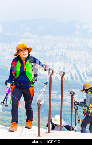 Koreanische Frauen tragen volle bunte Wanderbekleidung nähert sich Baegundae, Berg Bukhansan Berg mit Aussicht auf die Innenstadt Stockfoto