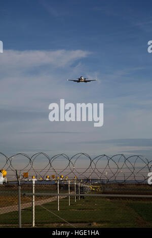 Ein Flugzeug fliegt über den Sicherheitszaun in Stuttgart Airport in Stuttgart, Deutschland. Stockfoto