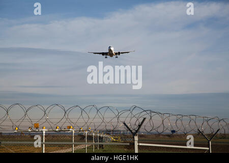 Ein Passagierflugzeug fliegt über den Sicherheitszaun in Stuttgart Airport in Stuttgart, Deutschland. Stockfoto