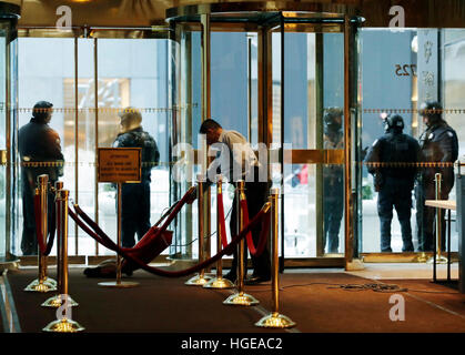 New York, USA. 8. Januar 2017. Ein Büroangestellter sieht der Boden in der Lobby des Trump Tower zu saugen, während New York City Polizisten Wache draußen in New York, USA, 8. Januar 2017 stehen. Bildnachweis: MediaPunch Inc/Alamy Live-Nachrichten Stockfoto