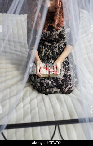 Junge Frau mit Postkarten im Bett Stockfoto