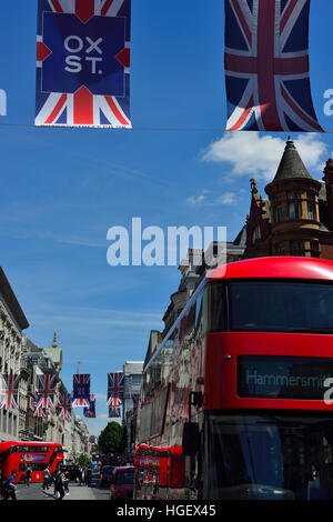 Oxford Street im Sommer mit Union Jack Flaggen und einem roten Bus, der die Straße entlang fährt. Stockfoto