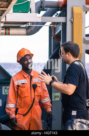 Freundschaft der Nationen an Bord des Schiff/Schiff. Europäischen Chief Officer anweist afrikanischer Seemann an Deck vor Job. Stockfoto