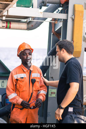 Freundschaft der Nationen an Bord des Schiff/Schiff. Europäischen Chief Officer anweist afrikanischer Seemann an Deck vor Job. Stockfoto