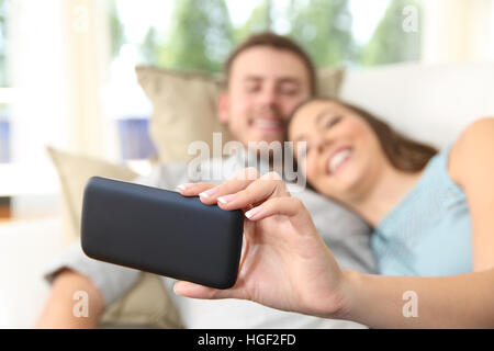 Nahaufnahme von ein paar beobachten Medien in einem Handy oder Selfies liegen in einer Couch zu Hause zu Stockfoto
