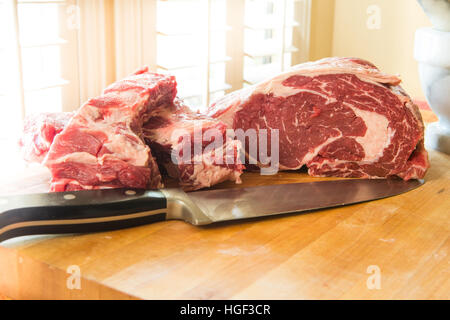 Schneiden frisches Rindfleisch Rib-Eye-Steaks auf einem Holzbrett Stockfoto