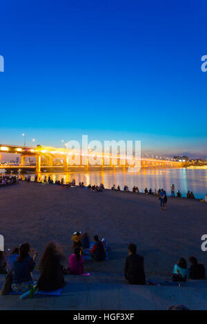 Leute zu beobachten Moonlight Rainbow Wasserbrunnen und bunte Lichtshow von Banpo-Brücke über den Fluss Han in der Abenddämmerung Stockfoto