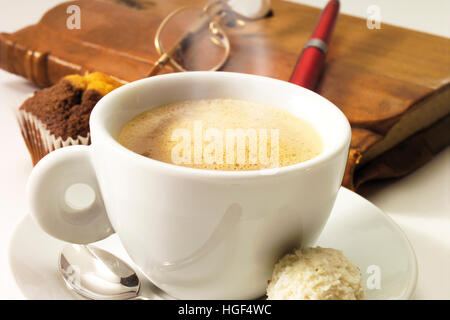 Kaffeepause: Kaffee, Buch, Stift und Gläser im Hintergrund Stockfoto