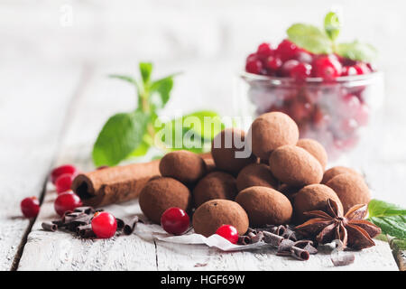 Hausgemachte gesunde vegane Schokolade Trüffel mit Cranberry auf Papier auf weißem Holz Hintergrund Stockfoto