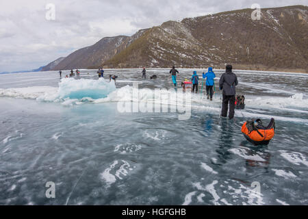 Baikalsee, Russland - 24. März 2016: Gruppe von Touristen Erwachsene und Kinder ist auf dem Eis des Baikal mit dem Schlitten Eis Übergang im 24. März Stockfoto