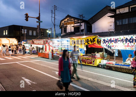 Die Menschen gehen vorbei an Ständen auf Bokushi Straße während einer Sommerfestivals in Shiozawa, Japan. Stockfoto