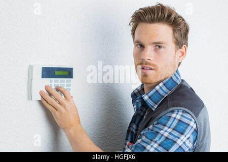 attraktive junge Handwerker prüft die Alarmanlage Stockfoto