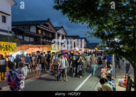 Die Menschen gehen vorbei an Ständen auf Bokushi Straße während einer Sommerfestivals in Shiozawa, Japan. Stockfoto