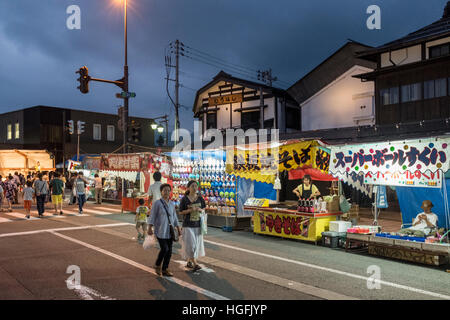 Die Menschen gehen vorbei an Ständen auf Bokushi Straße während einer Sommerfestivals in Shiozawa, Japan. Stockfoto