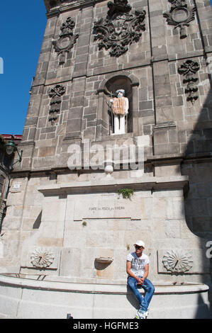 Porto, Portugal, Europa: Ein portugiesischer Mann sitzend auf Fonte da Praca da Ribeira, der Brunnen mit Blick auf den Praça da Ribeira (Fluss) Stockfoto