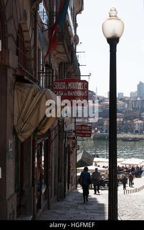 Porto: eine Straßenlaterne und einen alten Mann zu Fuß in Richtung der zentralen Praca da Ribeira mit Blick auf die Zeichen der Handwerksbetriebe Stockfoto